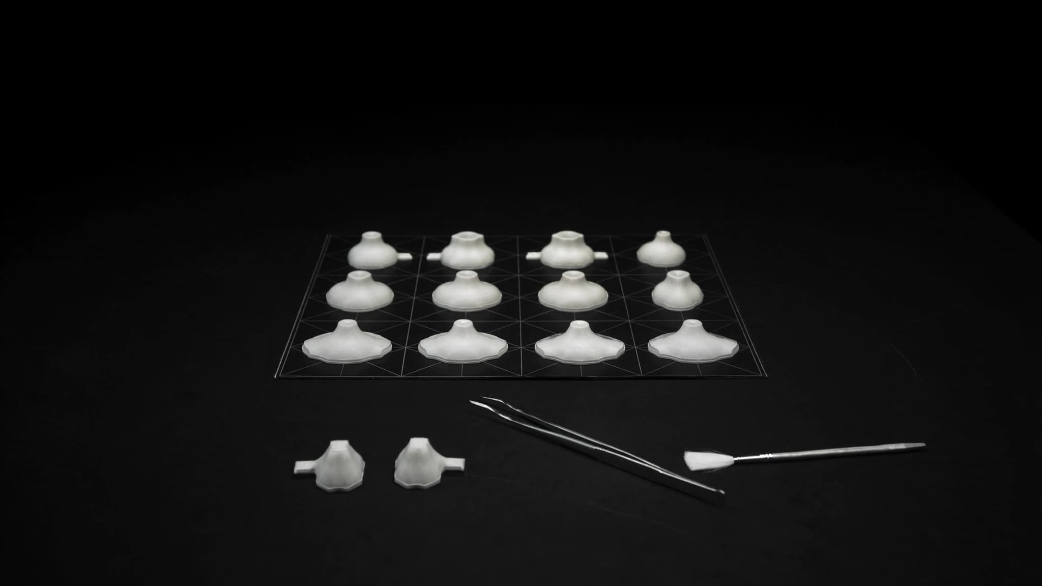 A grid of small test parts with tweezers and a brush