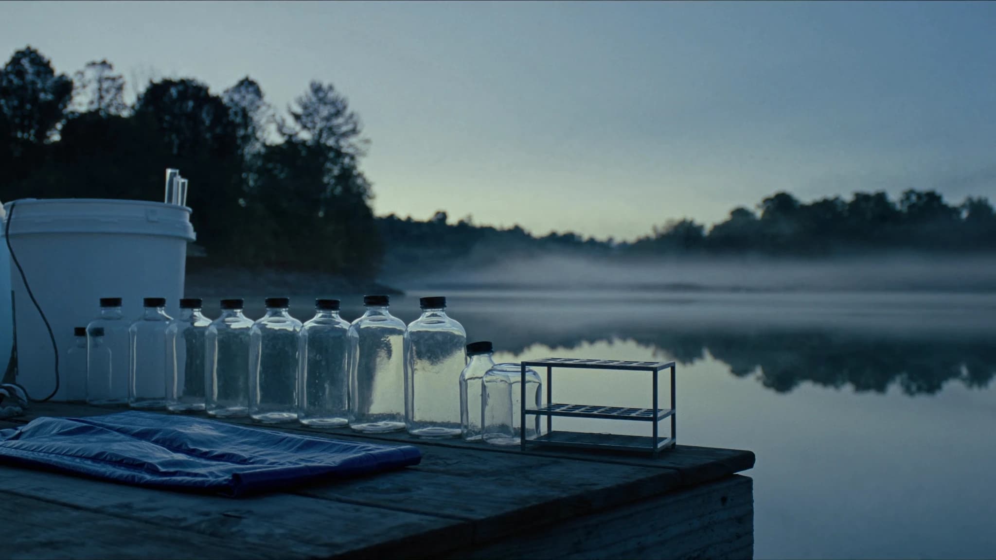 Sample bottles on a jetty at a misty reservoir at dawn