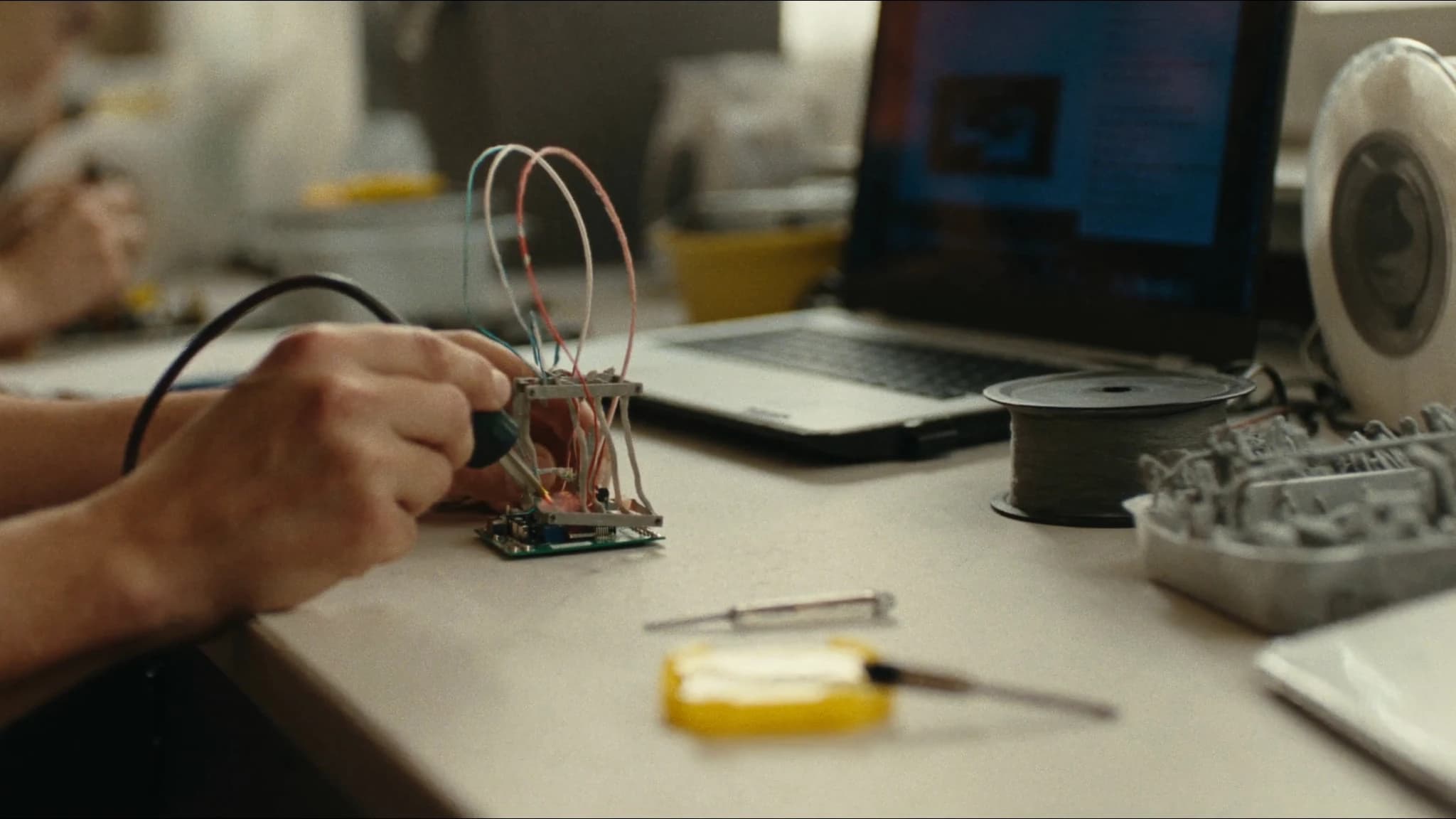 Hands assembling and soldering a small test frame in a teaching lab